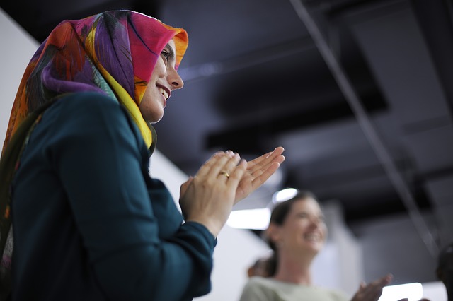 A woman wearing a hijab applauds